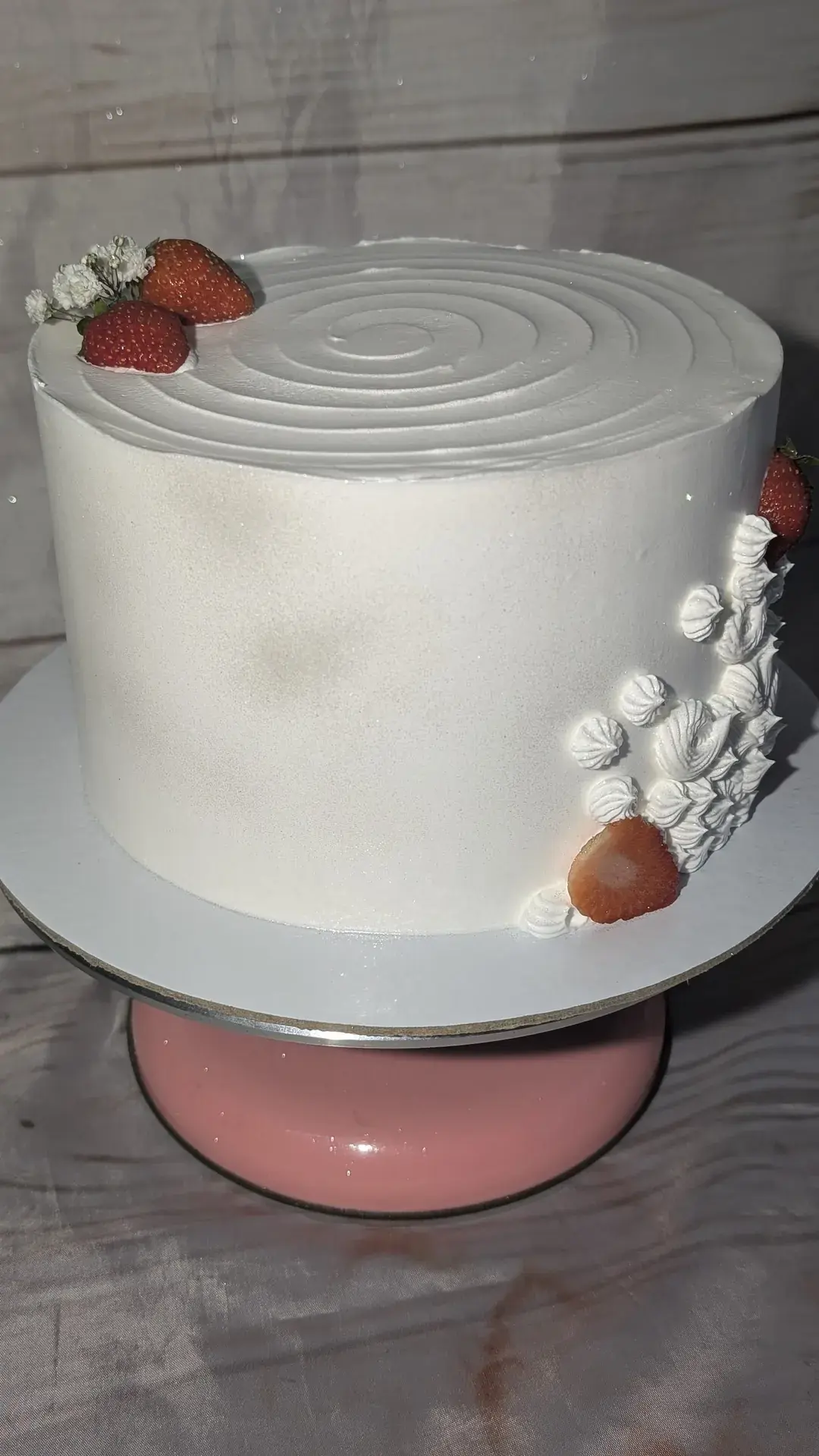 Bolo branco liso com espiral no topo e morangos frescos