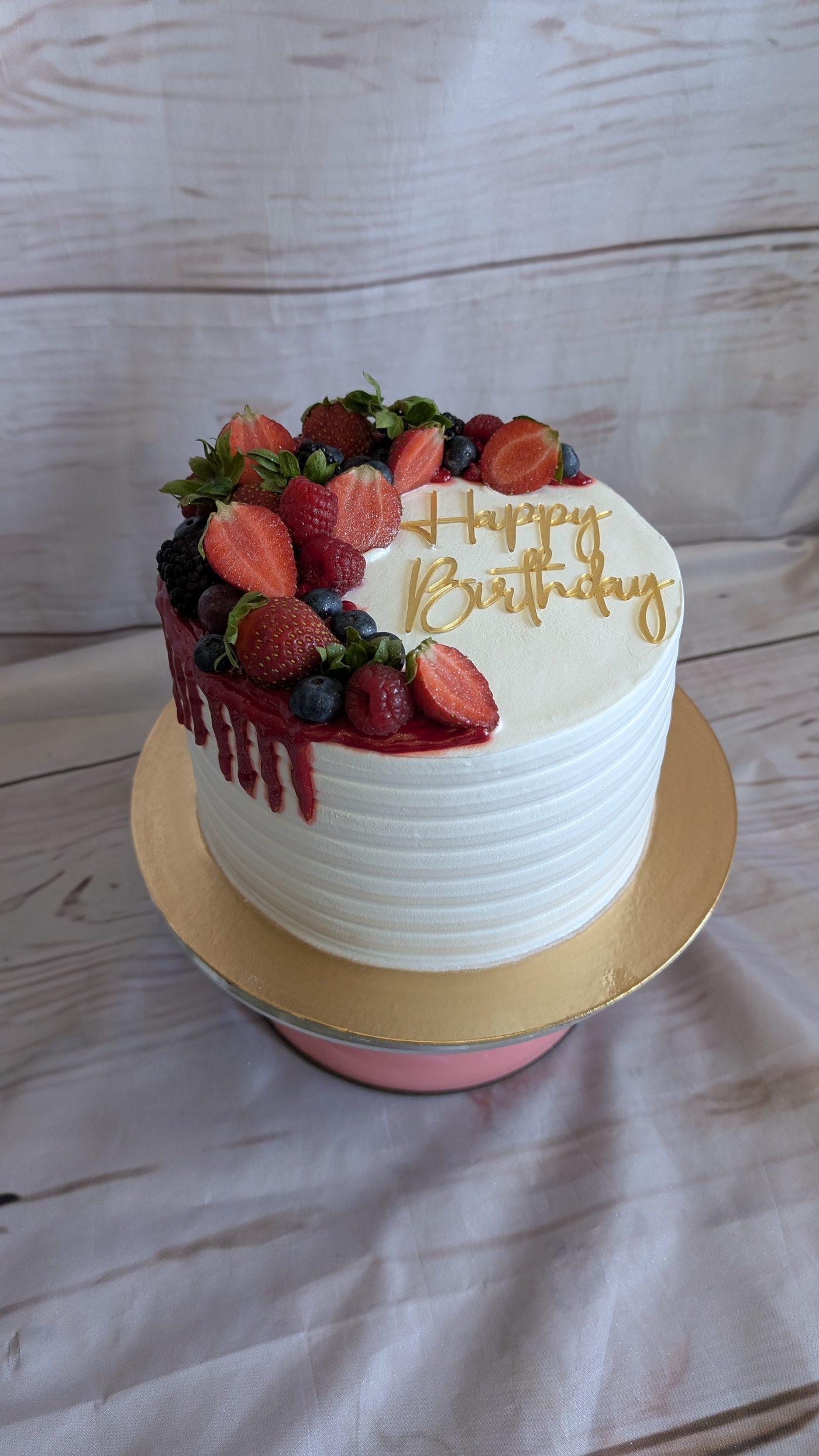 Bolo de aniversário branco com frutas vermelhas e topo Happy Birthday