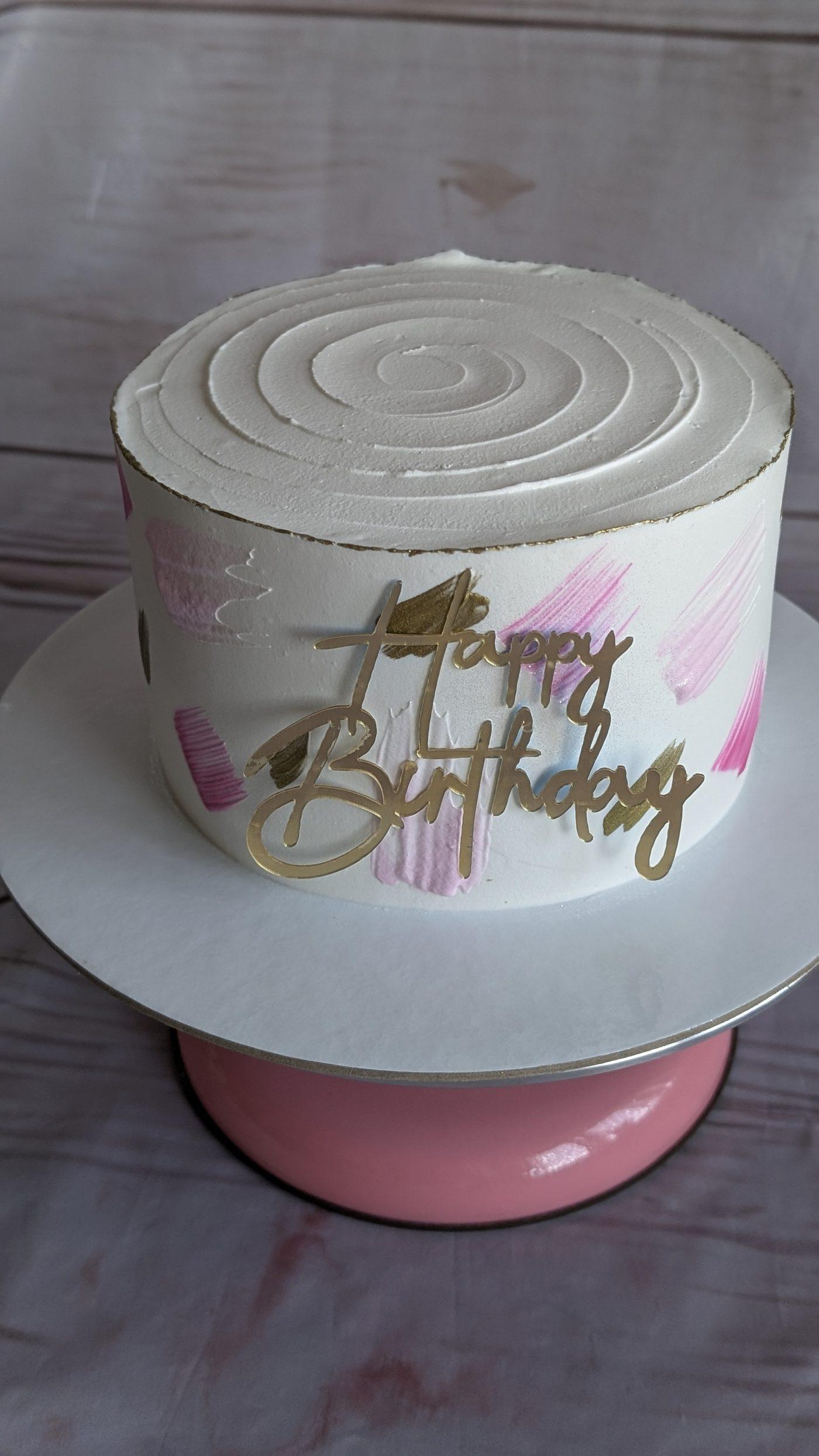 Bolo de aniversário branco com pinceladas rosa e topo Happy Birthday dourado