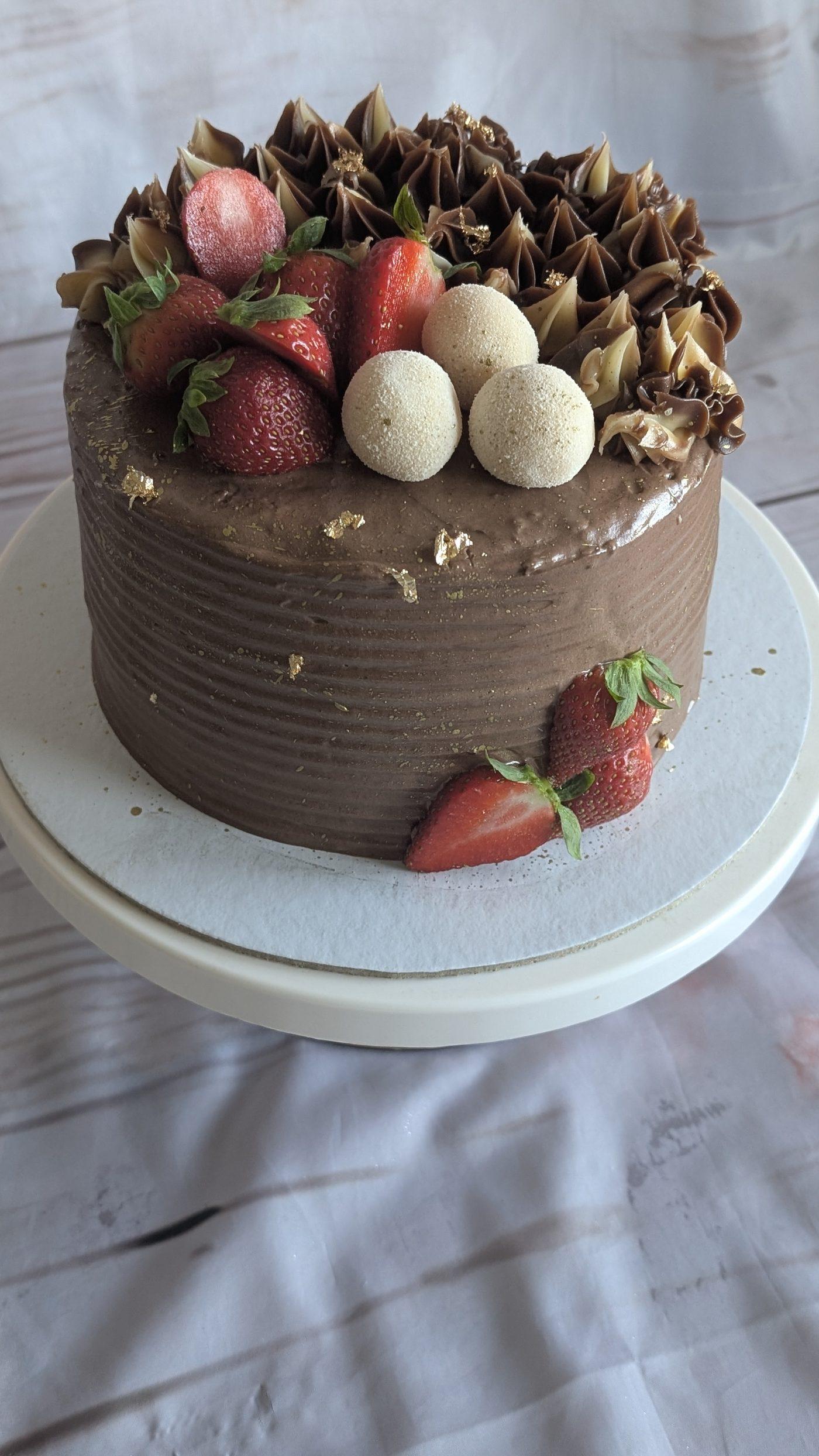 Bolo de aniversário chocolate com morangos, brigadeiros e folha de ouro