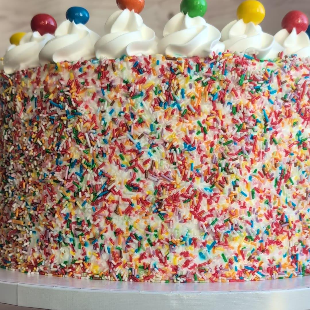 Bolo de aniversário coberto de granulado colorido com rosetas de chantilly e gomas — Roberta C Cakes